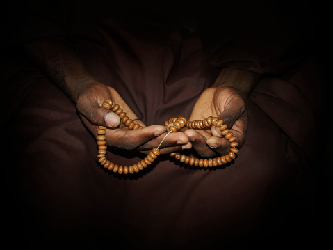 istock Muslim man wearing a brown djellaba and holding a rosary in his hands, photo, dark background 1465872407