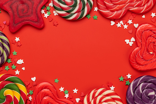 Various candy sweets and lollipops on red background and copy space for your text. Flat lay