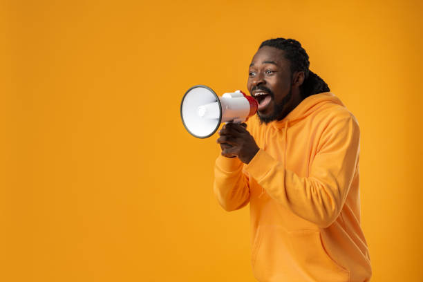 istock Young african man against yellow background with megaphone 1465879199