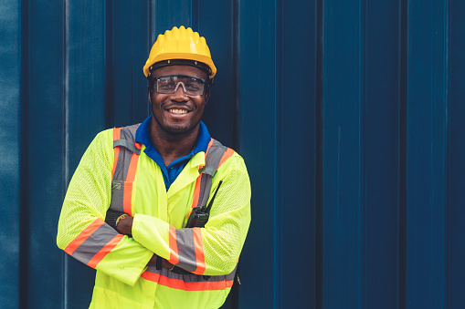 Young African American male worker at overseas shipping container yard . Logistics supply chain management and international goods export concept .
