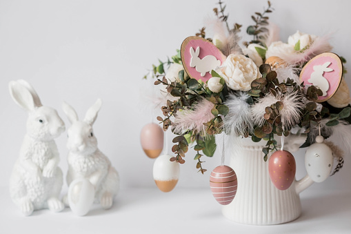 Banner. The concept of a bright Easter holiday. A bouquet of flowers with feathers and white rabbits on a white isolated background. Beautiful Easter card.