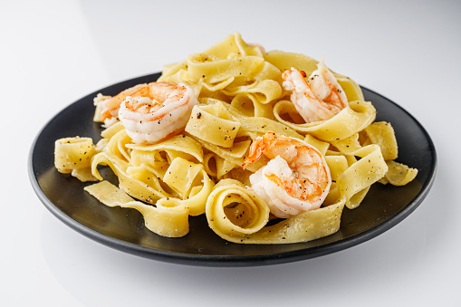 delicious shrimp fettuccine alfredo pasta on a white background.