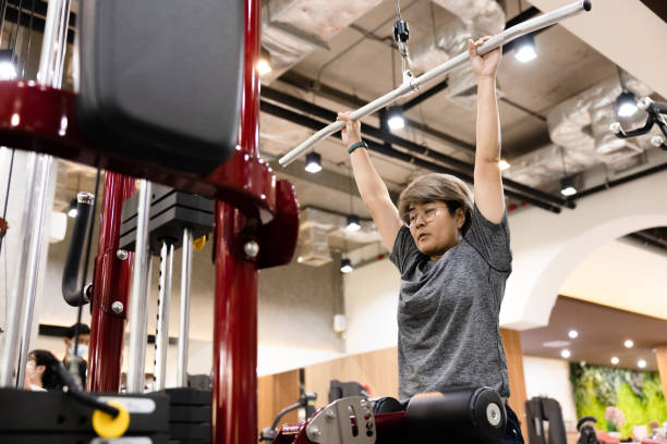 middle aged woman exercising Use a Lat Pulldown machine in the gym. stock photo