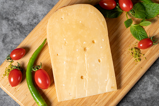 Gouda cheese. Piece of gouda cheese on wooden cutting board. Cheese collection. Ripe hard cheese made from cow's milk in the Netherlands. Top view
