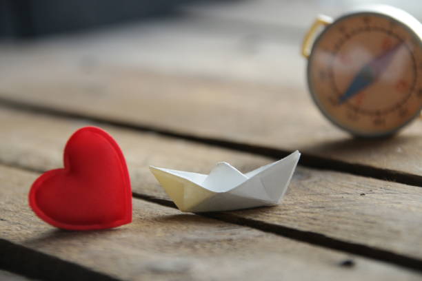 Red heart on a wooden background and paper boat. Place for text. Valentine. stock photo