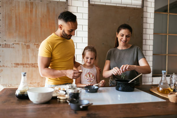 Multiracial family with one child cooking lunch in modern kitchen stock photo