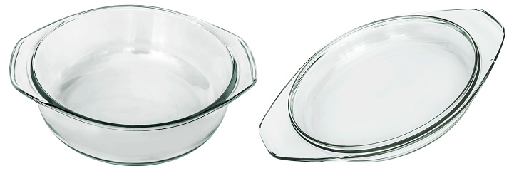 Studio shot of large empty round clear glass baking dish with its cover set aside, isolated on white background, side view.