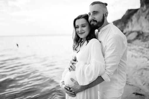 Studio shot of affectionate husband embracing his pregnant wife from behind