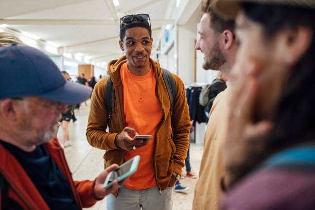 A group of people standing together in an airport in Toulouse, France. They are waiting to catch a flight while some of them use mobile phones.