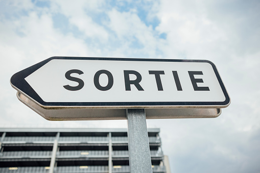 A directional sign outside at airport in Toulouse, France. It has the message 'sortie' on it, which translates to 'exit' in French.