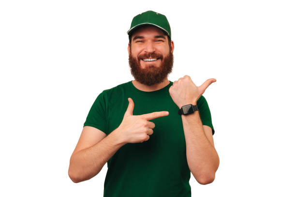 istock Cheerful delivery man wearing green uniform and smart watch points at it. 1465925576