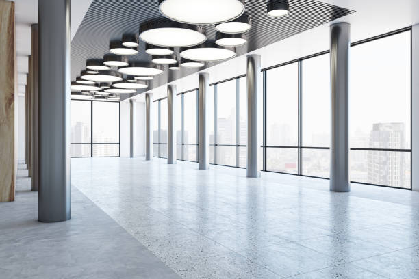 istock Perspective view on panoramic window with city view background in modern business center hall with illuminated round lamps and metallic pillars on concrete floor. 3D rendering 1465929348