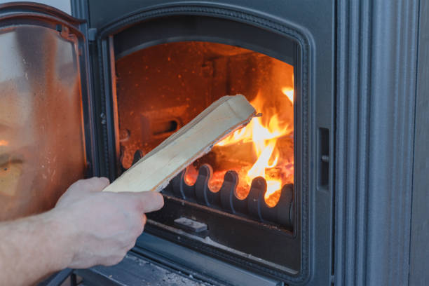 istock A man throws firewood into a cast-iron stove-fireplace. Close-up view. 1465929656