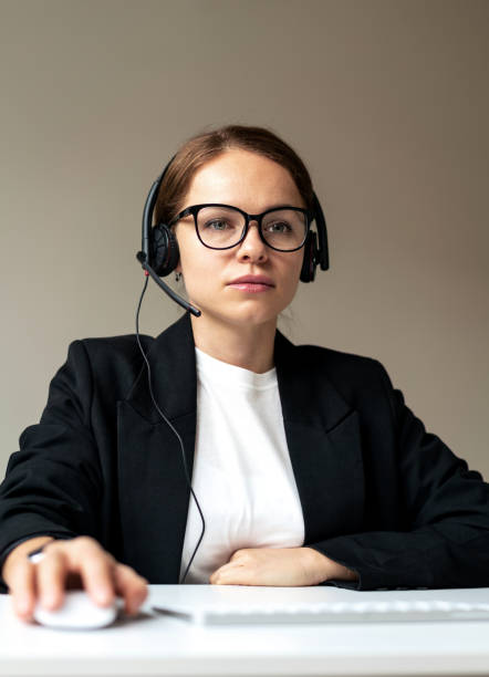 istock Serious woman office worker in glasses and headset sitting at desk working at computer. 1465931256