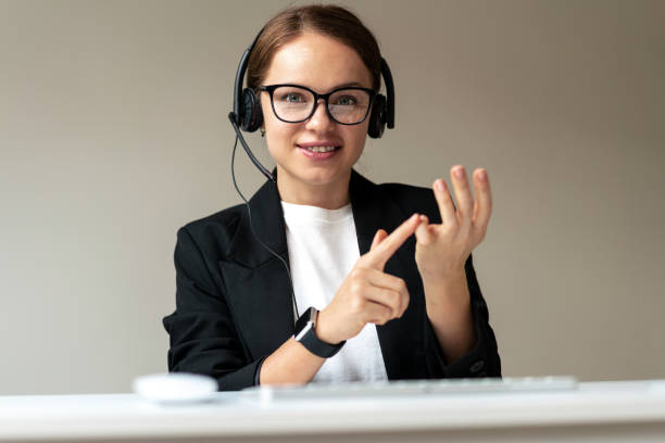 Video call with personal development coach, woman in glasses and headset looking at webcam counting with fingers.