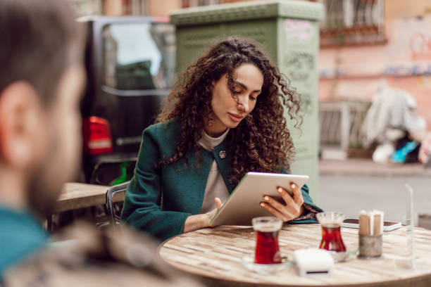 istock Beautiful curly businesswoman using digital tablet outdoors in cafe 1465935316