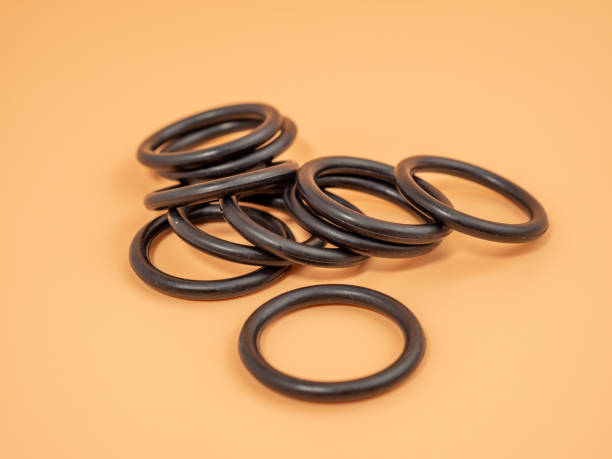 istock Hydraulic and pneumatic o-rings in black in different sizes on an orange background. Rubber gaskets for plumbing. 1465935517