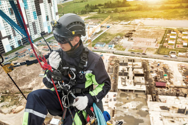 istock Industrial mountaineering worker in uniform talking walkie-talkie hangs on wall skyscraper at buildings backdrop 1465938382