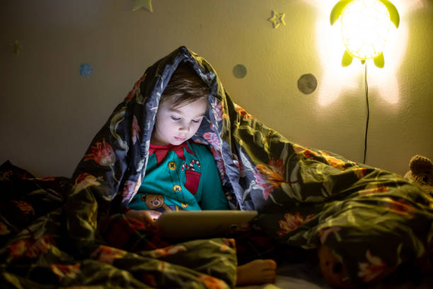 istock Cute preschool child, playing on tablet at home in bed 1465939751