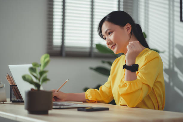 istock Asian woman working online using laptop and making note at home office. 1465943469
