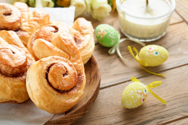 Easter breakfast Holliday concept. Easter bunny buns rolls with cinnamon made from yeast dough with orange glaze, easter decorations, colored eggs on old wooden background. Easter Holliday card. desayuno de pascua concepto holliday. rollos de bollos de conejo de pascua con canela hechos de masa de levadura con glaseado de naranja, decoraciones de pascua, huevos de colores sobre fondo de madera vieja. tarjeta de vacaciones de pascua.