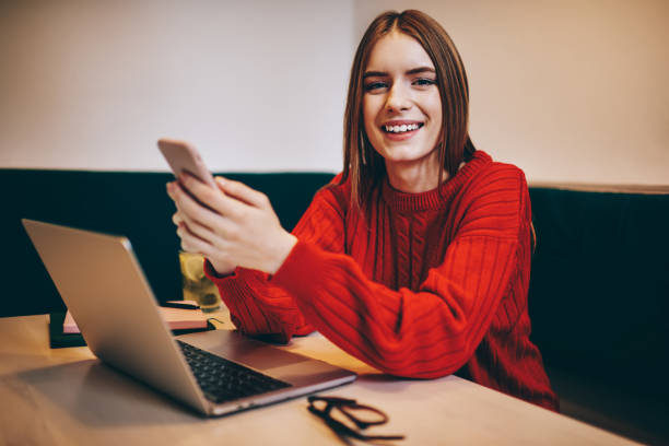 istock Positive female freelancer text messaging via smartphone and working on laptop 1465946887
