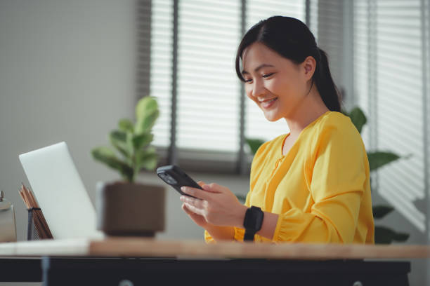 istock Asian woman enjoy with working online and using smartphone sitting at home office. 1465949552