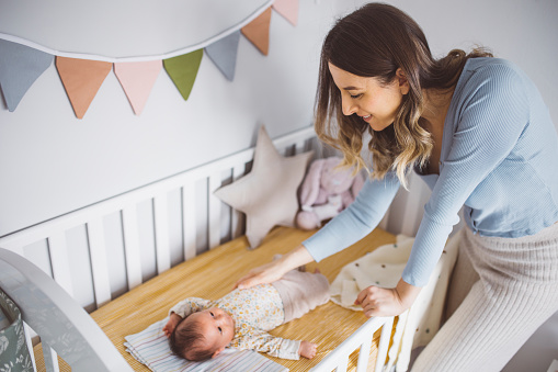 Mother with her cute baby girl in her crib.