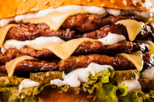 abstrakcyjne śmieciowe jedzenie. poczwórny burger z serem, ogórkiem i sałatą. tekstura tła fast food. - cheeseburger zdjęcia i obrazy z banku zdjęć