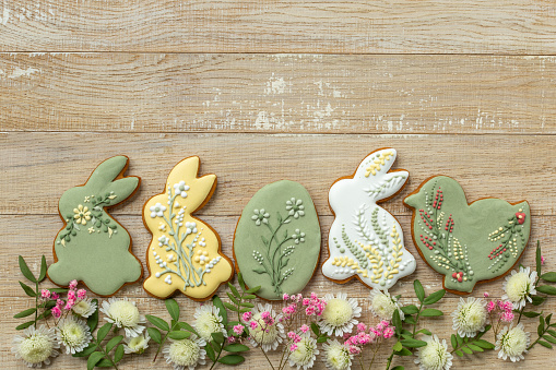 wooden background with easter icing cookies and flowers. Sweet food and Easter holiday concept. Flat lay.  top view, copy space