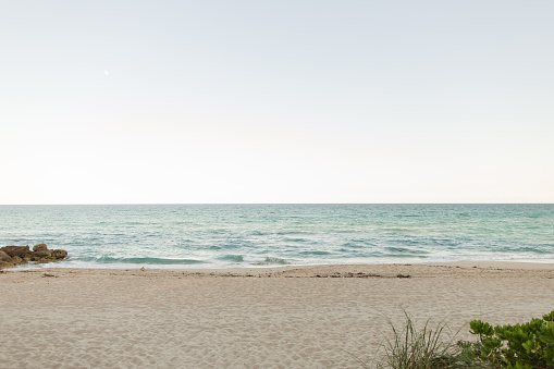 Peaceful waves lap onto a sandy beach as heavy storm clouds roll in over a calm Lake Michigan on this relaxing evening at Kirk Park. Tranquil shoreline seascape background with copy space.