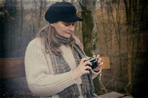 Mid adult woman with hat photographing in forest.