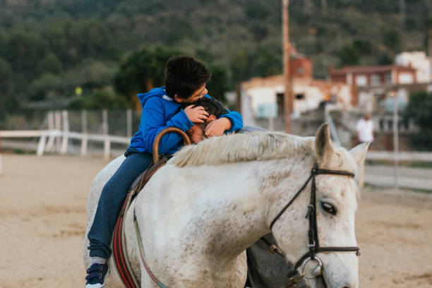 istock Boy with disabilities sitting on a horse while embracing his equine therapy instructor. 1465982030