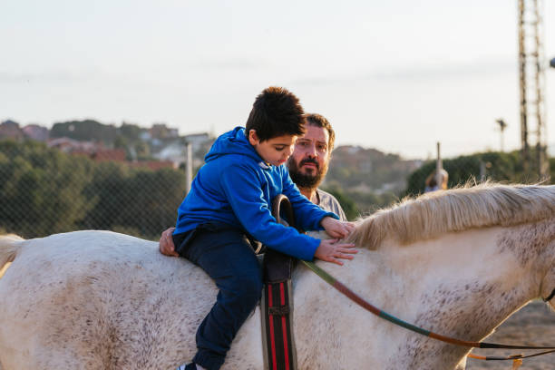 istock Boy with disabilities riding a horse during an equine therapy session with a male instructor. 1465984481