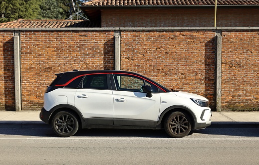 Udine, Italy. February 14, 2023. New Opel Mokka, subcompact crossover suv of the german automaker, on brick wall background. Side view.