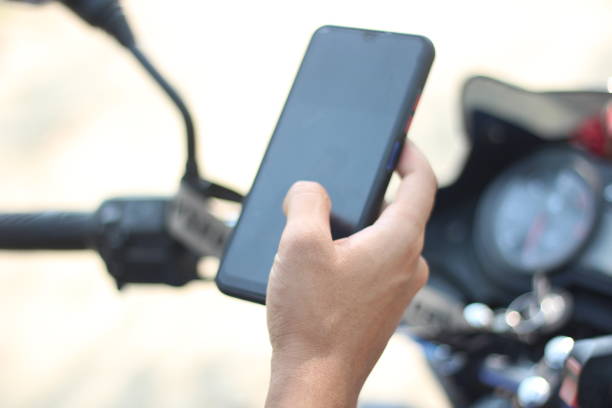 istock Here is a man sitting on a motorcycle holding a mobile and the background behind him is blurred 1465995590