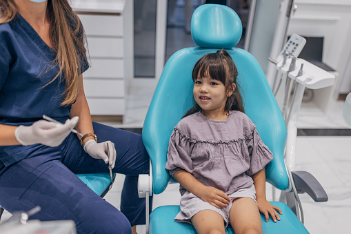 Little girl patient is sitting in dentist chair in dentist's office.