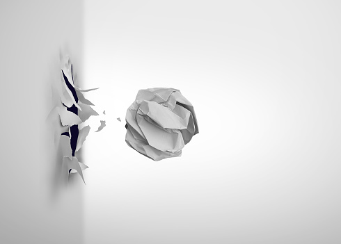 Business Frustration and office problems idea as a crumpled paper Breaking through and blasting out of a wall as a symbol to overcome obstacles and achieving despite difficulties as a success and brainstorming metaphor.