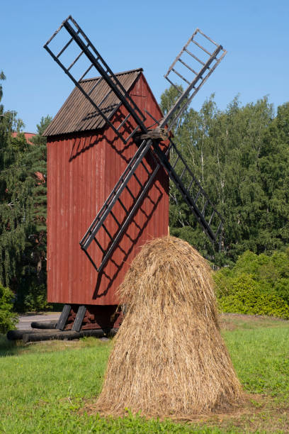 Old red wooden windmill with a haystack in the foreground. Finnish agriculture. stock photo