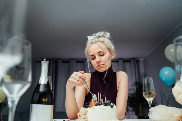 zdenerwowana, nieszczęśliwa atrakcyjna kobieta jedząca świąteczne ciasto podczas świętowania urodzin w domu, siedząca samotnie przy serwowanym stole, odwracająca wzrok, śniąca. selfparty, znudzona impreza. selektywne ustawianie ostrości - women celebration wine party zdjęcia i obrazy z banku zdjęć