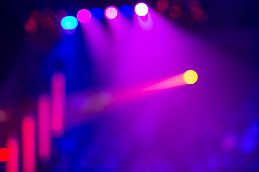 Multi-colored blurred bokeh spots and light rays from the stage light.
