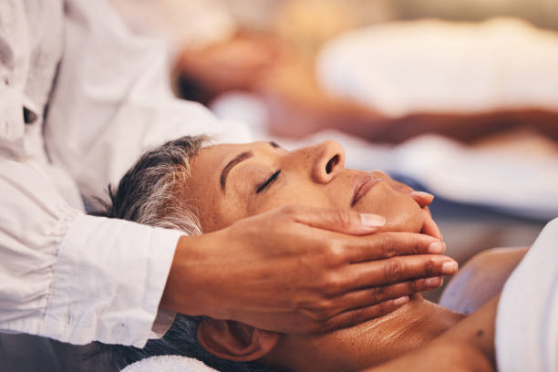 masaje facial, mujer y relax en spa para el bienestar, cosmetología de lujo y cosméticos zen. estética facial, salón de belleza y fisioterapia para el cuidado saludable de la piel de una mujer madura con dermatología corporal - head massage massaging facial massage beautician fotografías e imágenes de stock