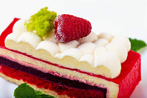 Multilayer cake with raspberry berry on white plate close up