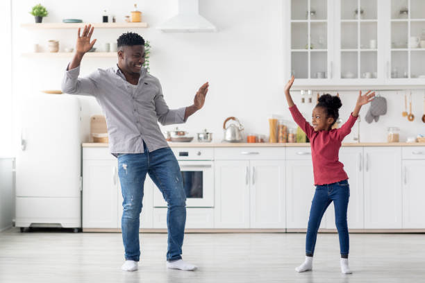istock Funny african american father and daughter damcing at kitchen 1466026069