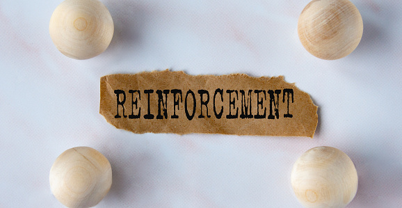 REINFORCEMENT - word on a brown torn piece of paper on a light background with balls. Business reinforce your business security concept.