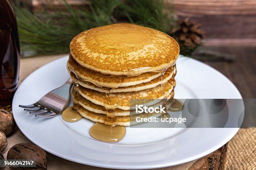 istock Stack of buttered pancakes on a plate with a dark and rustic wood log cabin setting 1466042147