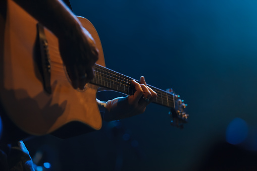 Hand of a musician playing a guitar in backlit
