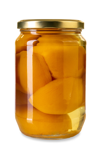 Peaches in syrup canned in glass jar with golden colored cap. Isolated on white with clipping paht included