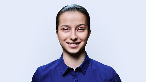 Portrait of teenager girl looking at camera on white studio background. Smiling teenage female 15, 16 years old. Adolescence, high school student, photo for documents, student travel card