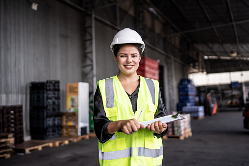 Portrait of a young woman holding a clipboard in a warehouse